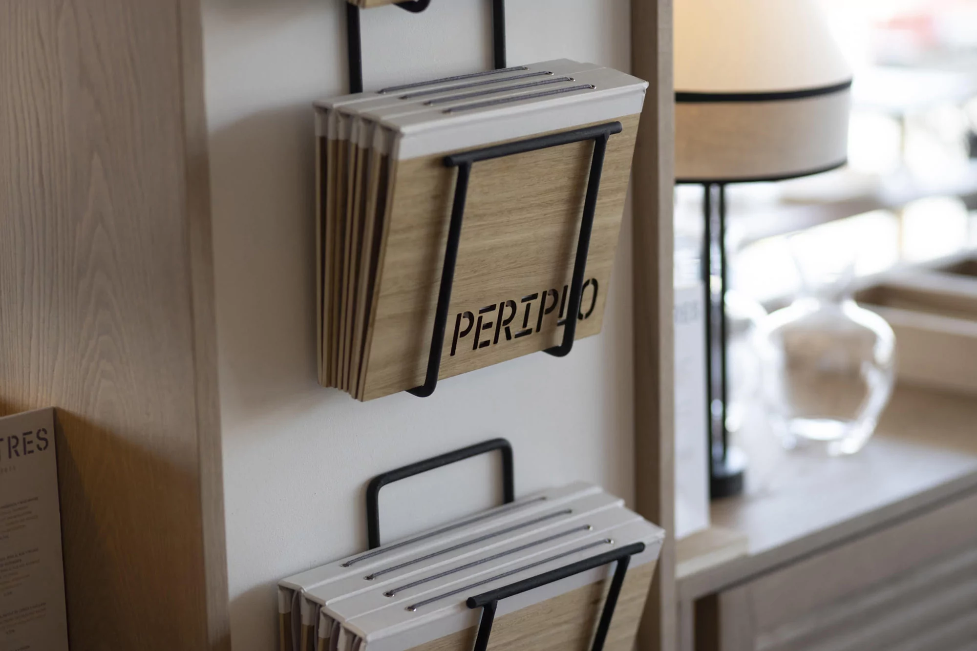 Magazine rack on wall with wooden boards in black metal frame. Books and magazines displayed on shelf; indoor, interior design.