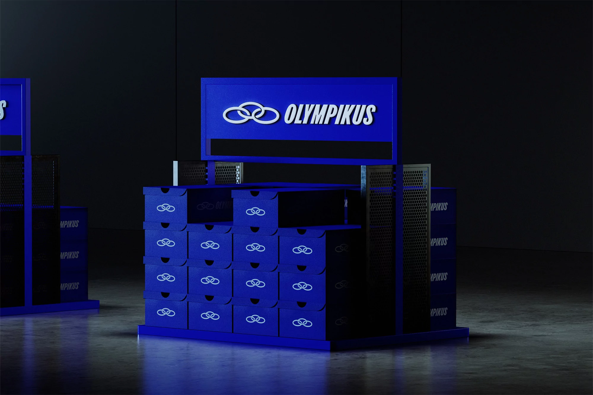 Eye-level studio shot of shoe-box displays, featuring blue boxes with the Olympikus logo, set against a dark, neutral background.
