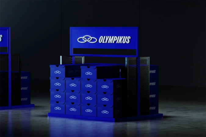 Eye-level studio shot of shoe-box displays, featuring blue boxes with the Olympikus logo, set against a dark, neutral background.