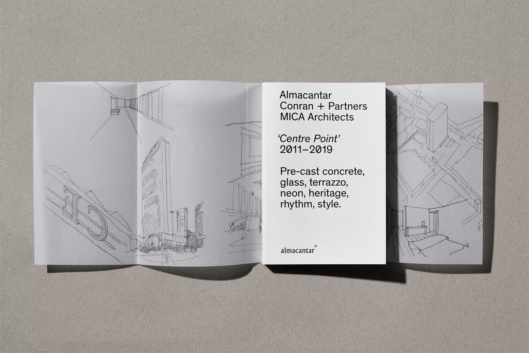 Architectural sketches of buildings and interiors are displayed in an open brochure on a textured gray surface, featuring clean lines and shadows.