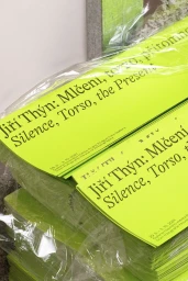 Stacks of bright yellow printed posters wrapped in clear plastic showing typography