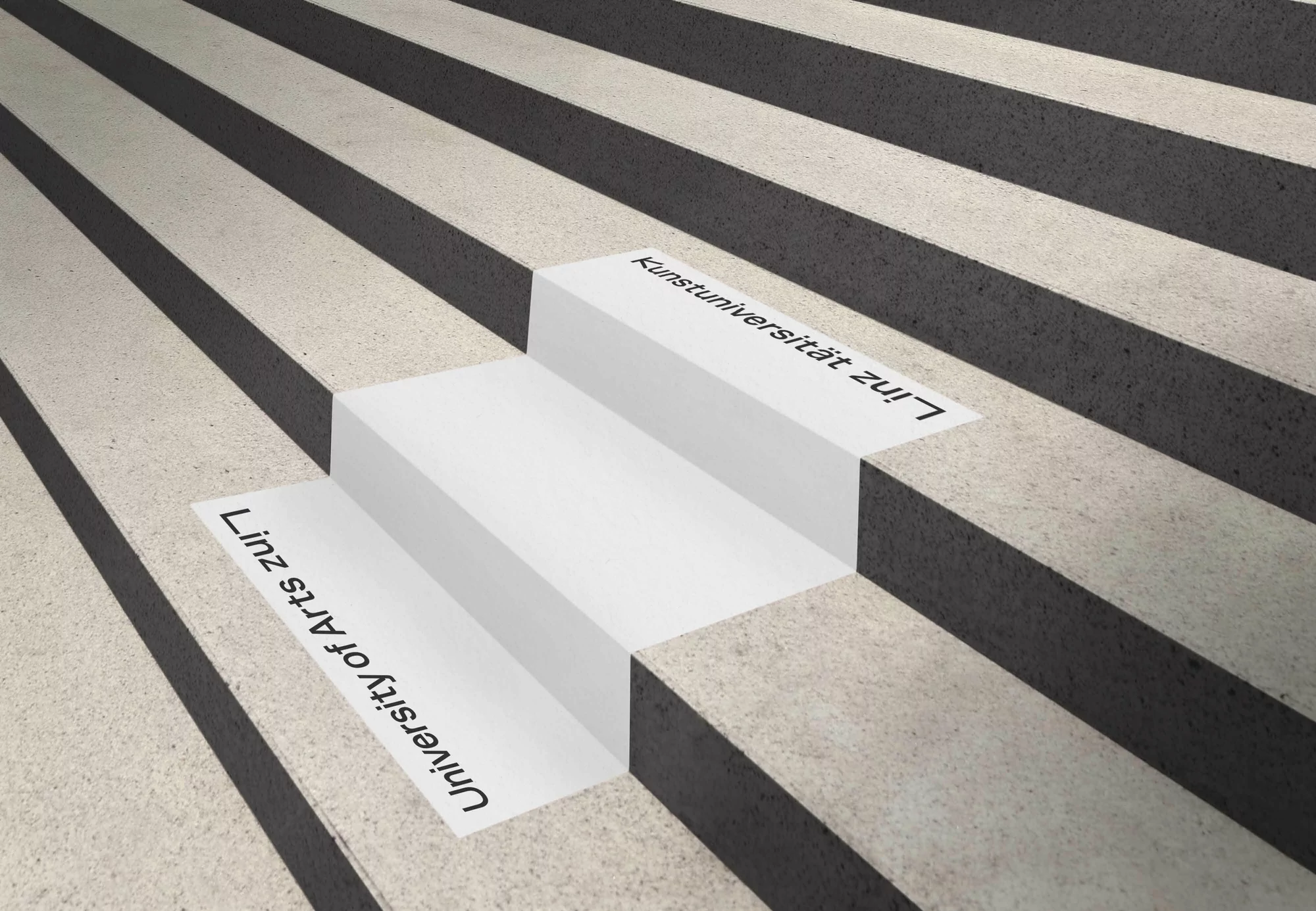 Architectural image features a staircase with alternating black and light grey steps, adorned with white text decals on each step.