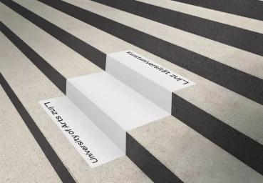 Concrete stairs featuring alternating light and dark treads with institutional typography reading University of Arts Linz
