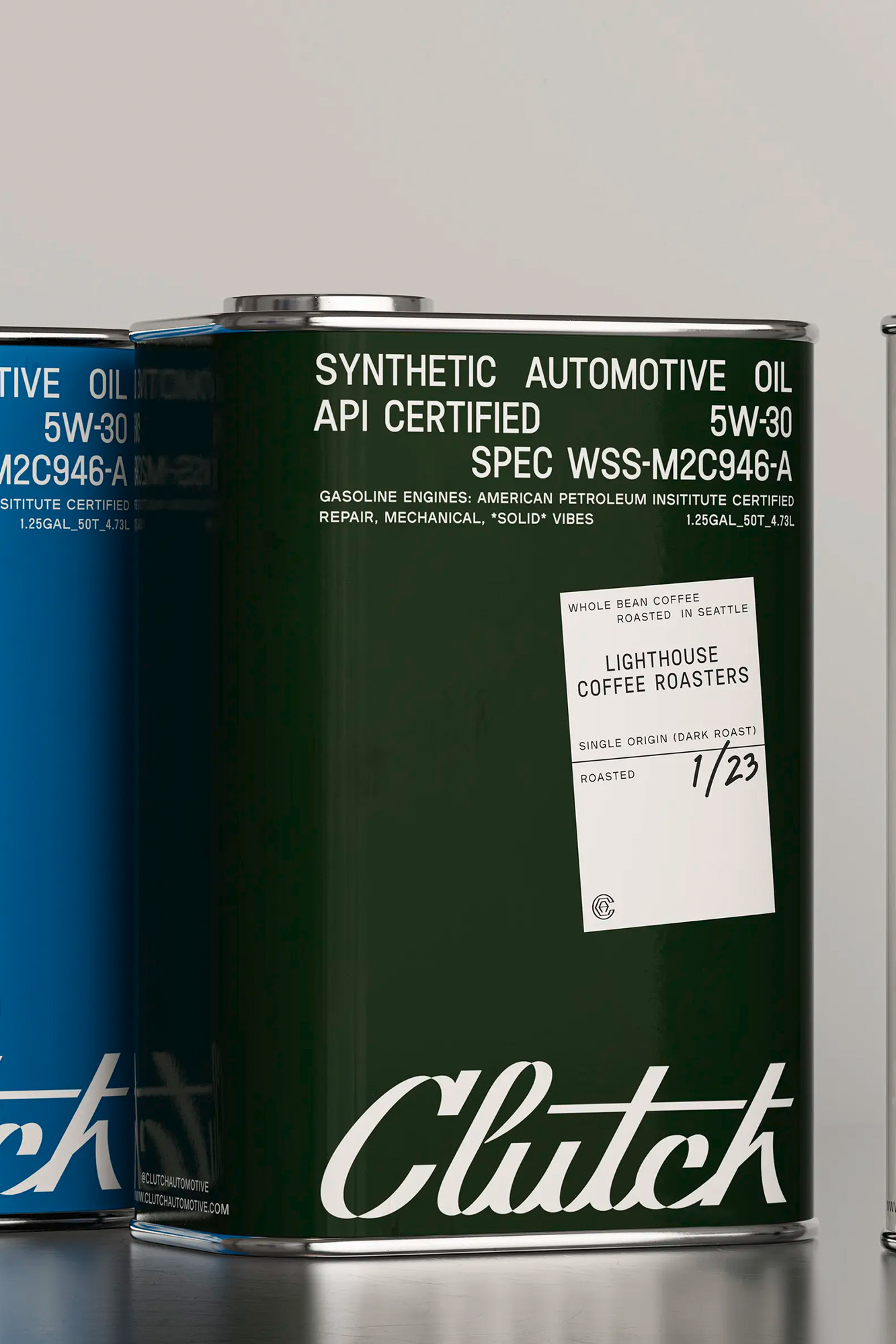 Close-up of a green automotive oil canister with a label for Lighthouse Coffee Roasters, next to a blue automotive oil canister.