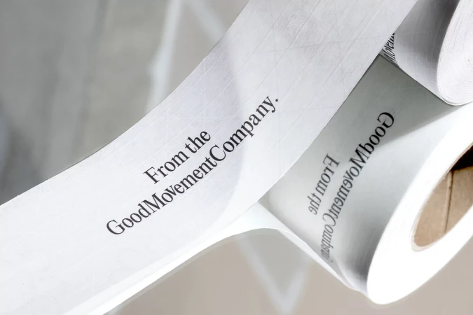 Close-up studio shot of rolled white paper with the text 'From the GoodMovementCompany' printed in black ink for brand messaging.