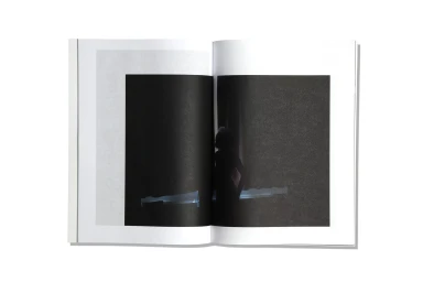 An open magazine spread displaying a minimalist dark photography print against a clean white background