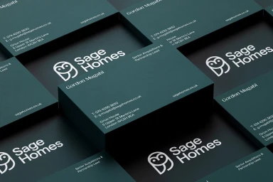 Stack of dark green business cards featuring white Sage Homes owl logo and contact information