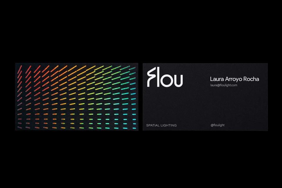 Close-up of two business cards, one with a geometric pattern in rainbow colors, and the other with the company information.