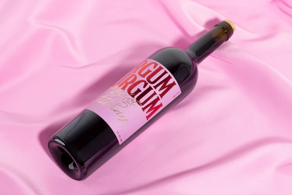 Studio shot of a wine bottle on a pink silk background with creative label and dark red wine for food and beverage purposes.