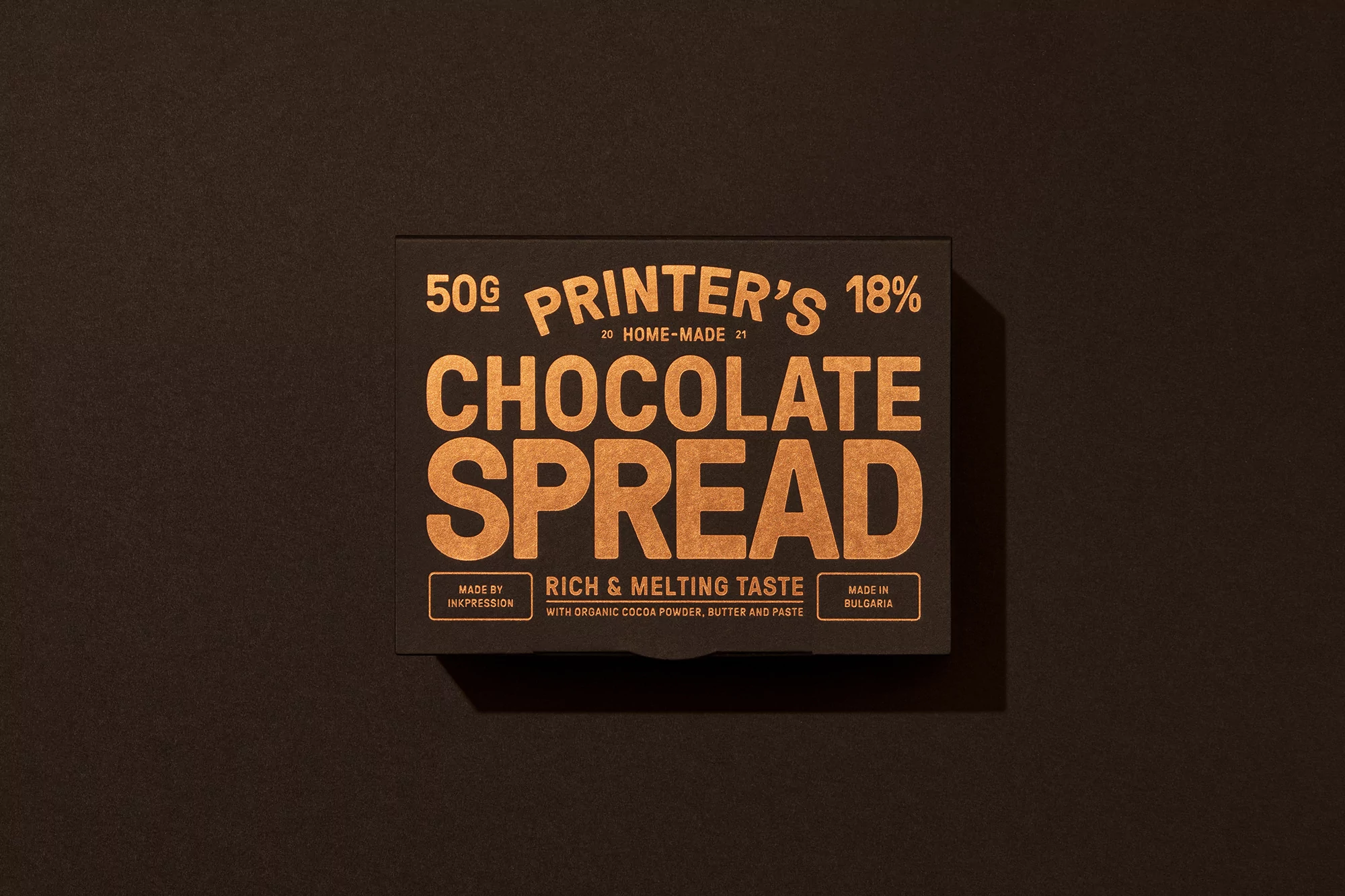 Chocolate spread packaging on a dark surface with gold lettering. Text includes the brand name and flavor details.