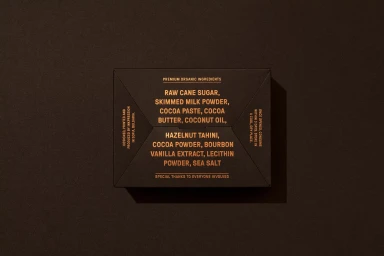 Top-down view of a dark rectangular packaging box featuring printed copper-colored typography on a dark brown textured background.