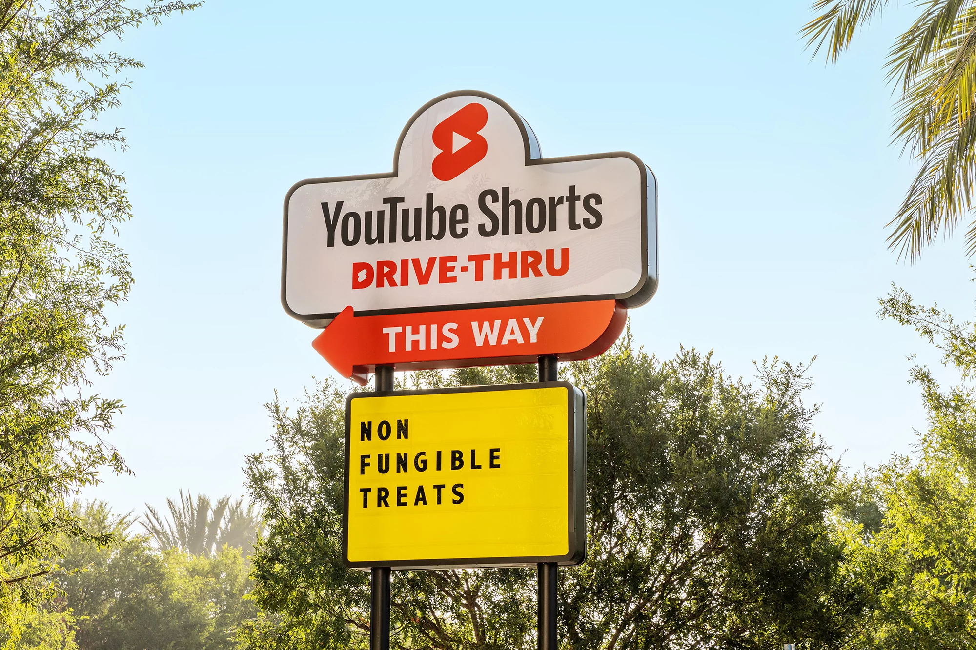 Youtube Shorts drive-thru sign with digital treats advertisement in front of trees and sky on a sunny day. Marketing concept.