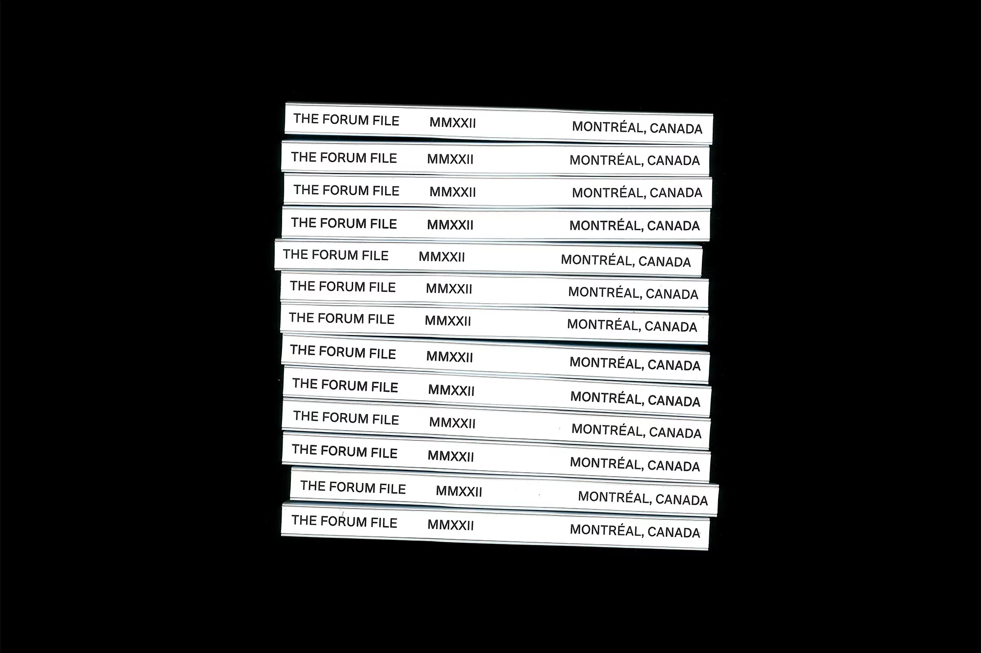 Stack of white cards with black text 'The Forum File MMXXII Montréal, Canada' on a black background, creating a high-contrast image.