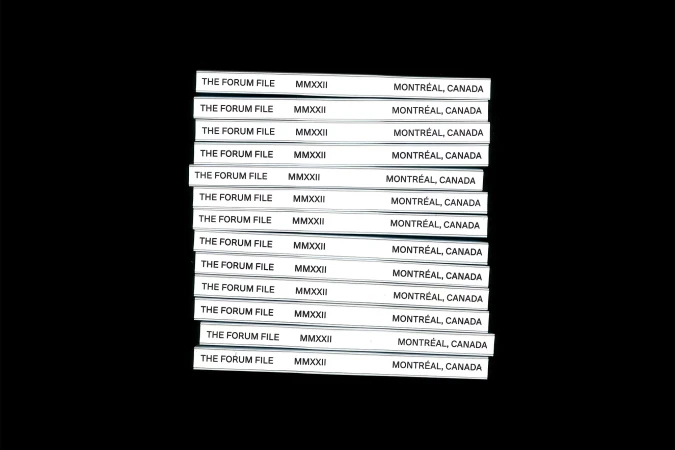 Stack of white cards with black text 'The Forum File MMXXII Montréal, Canada' on a black background, creating a high-contrast image.