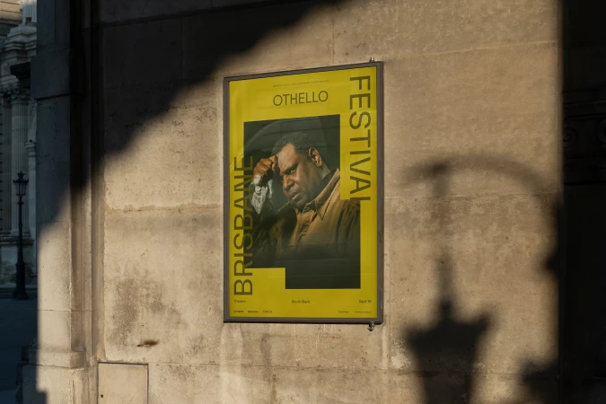Brisbane Festival poster featuring an African American man in the Othello play, mounted on an exterior building wall.