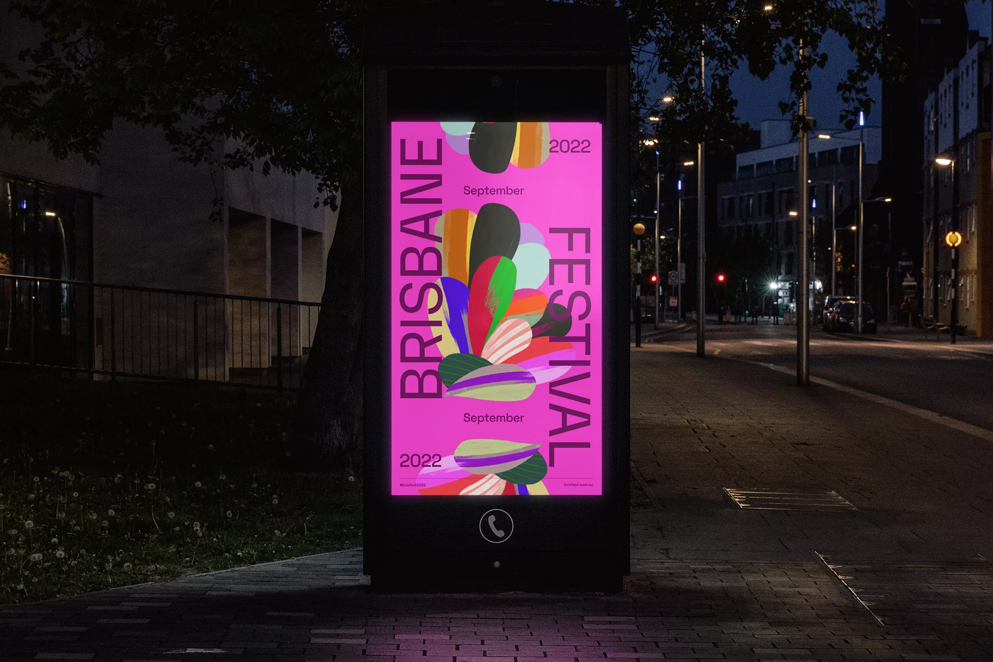 Outdoor advertising display featuring an artistic poster for the Brisbane Festival on a city street at night.