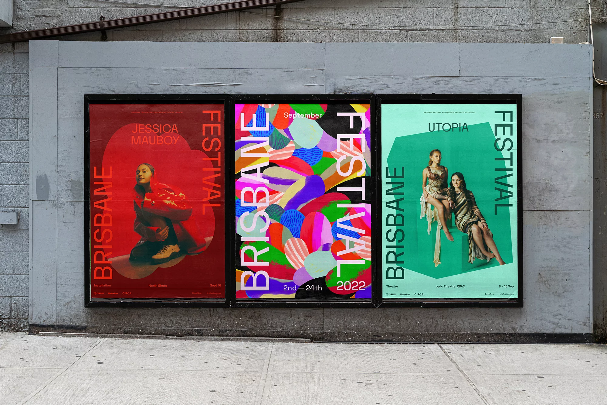 Three vibrant posters for the Brisbane Festival displayed on a textured grey wall, showcasing diverse designs and bold typography.