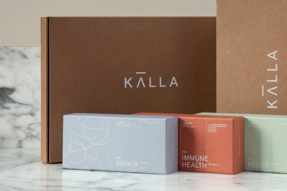 Kalla brand product boxes on a marble surface, promoting repair, immune health, and relief, with neutral brown color palette.