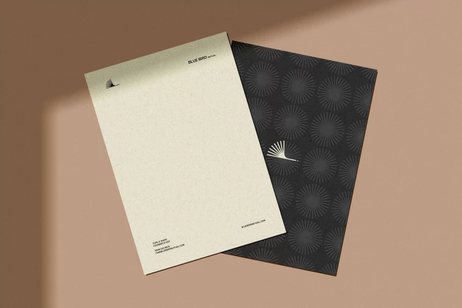 Minimalist product shot featuring stationery branding mockup with letterhead and envelope with geometric pattern on a brown surface.