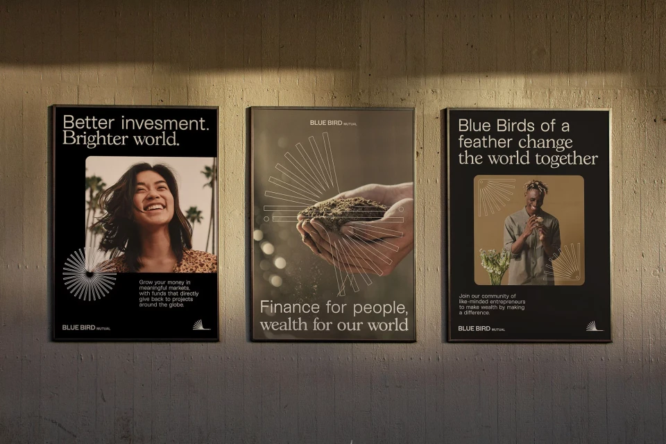Three posters on a concrete wall: one with a smiling woman, another with hands holding soil, and the third with a smiling man.