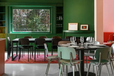 Interior view of Chandigarh Café featuring dark wooden chairs, a round black dining table, and rich green walls.