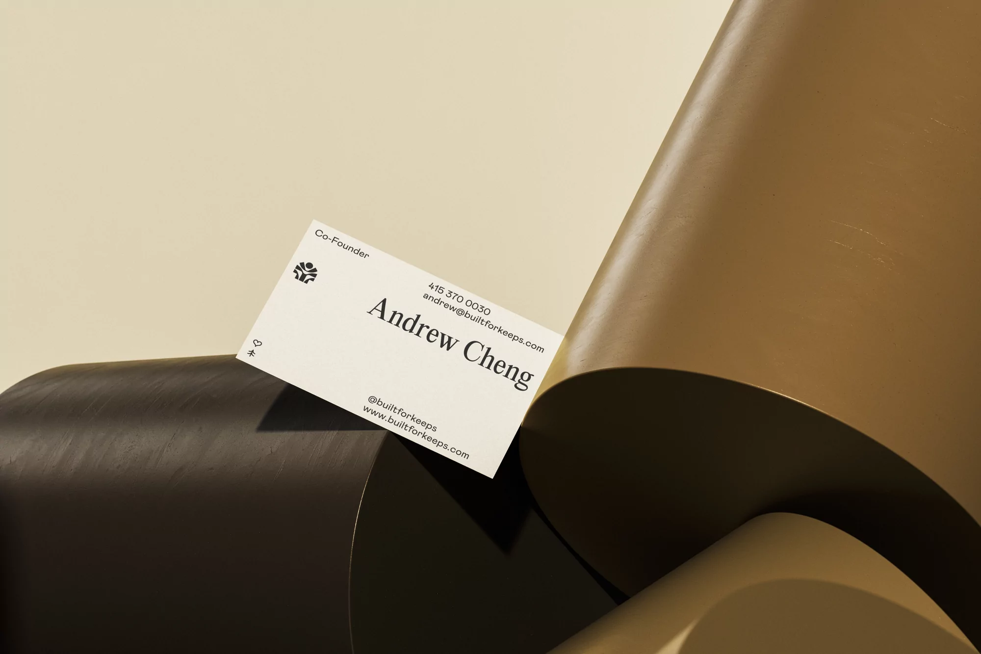 Business card with black and white design on a cream background, featuring name, title, contact information, and company logo. 