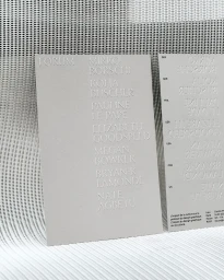 Embossed typography on grey card stationery standing against a textured metallic background.
