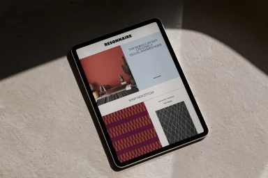 Tablet resting on a textured concrete surface displaying a digital brand interface with typography and imagery under natural light.