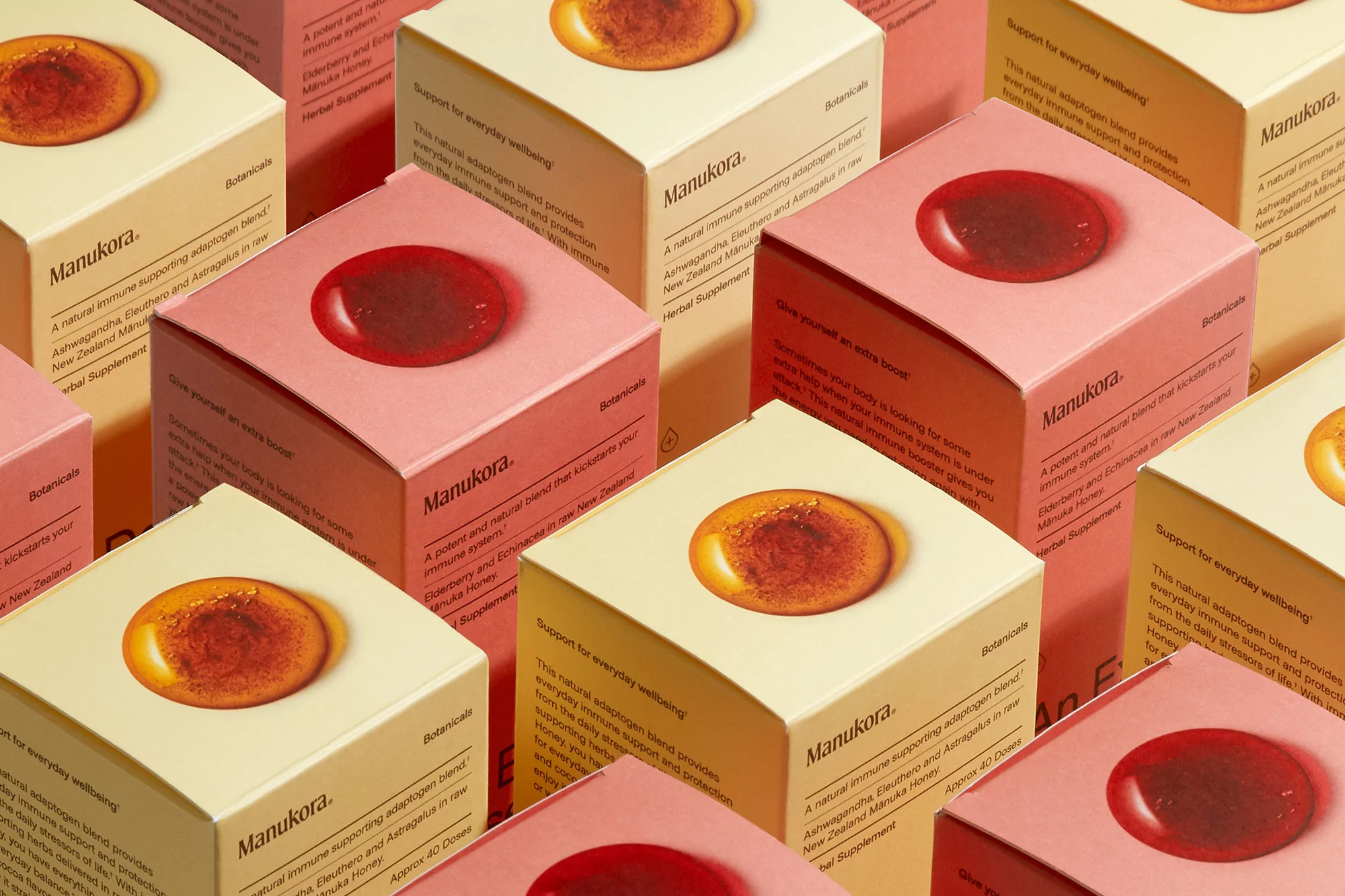 Collection of Manukora herbal supplement boxes in warm tones with a single gel capsule on top, photographed in a studio setting.