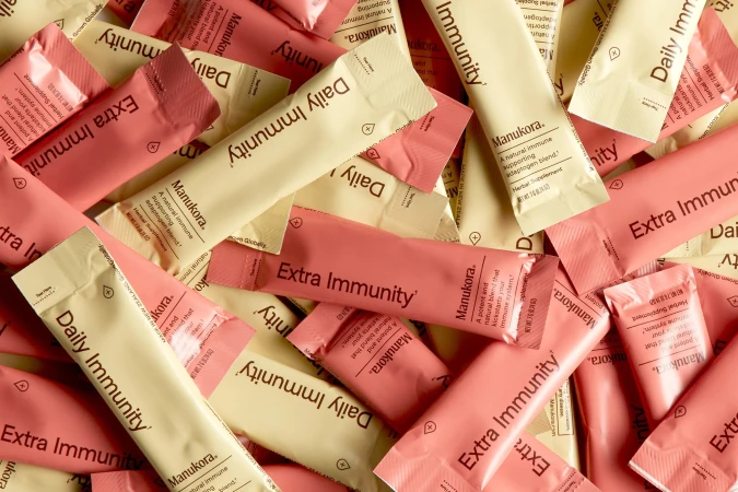 Close-up of tan and pink immunity supplement packets with brand and type names arranged randomly, with focus on product names.
