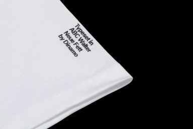 Close-up of folded white fabric with black typographic text set against a solid black background.