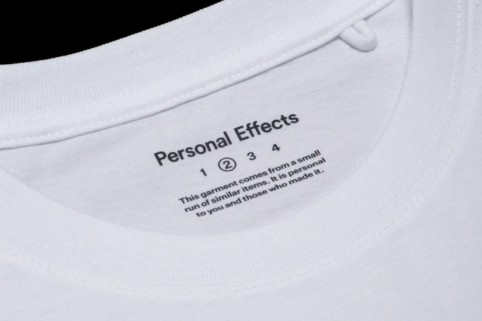 Close-up of a white t-shirt collar showing printed brand name and text label inside the neckline.