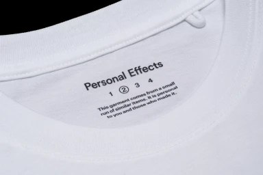 Close-up of a white t-shirt collar showing printed brand name and text label inside the neckline.