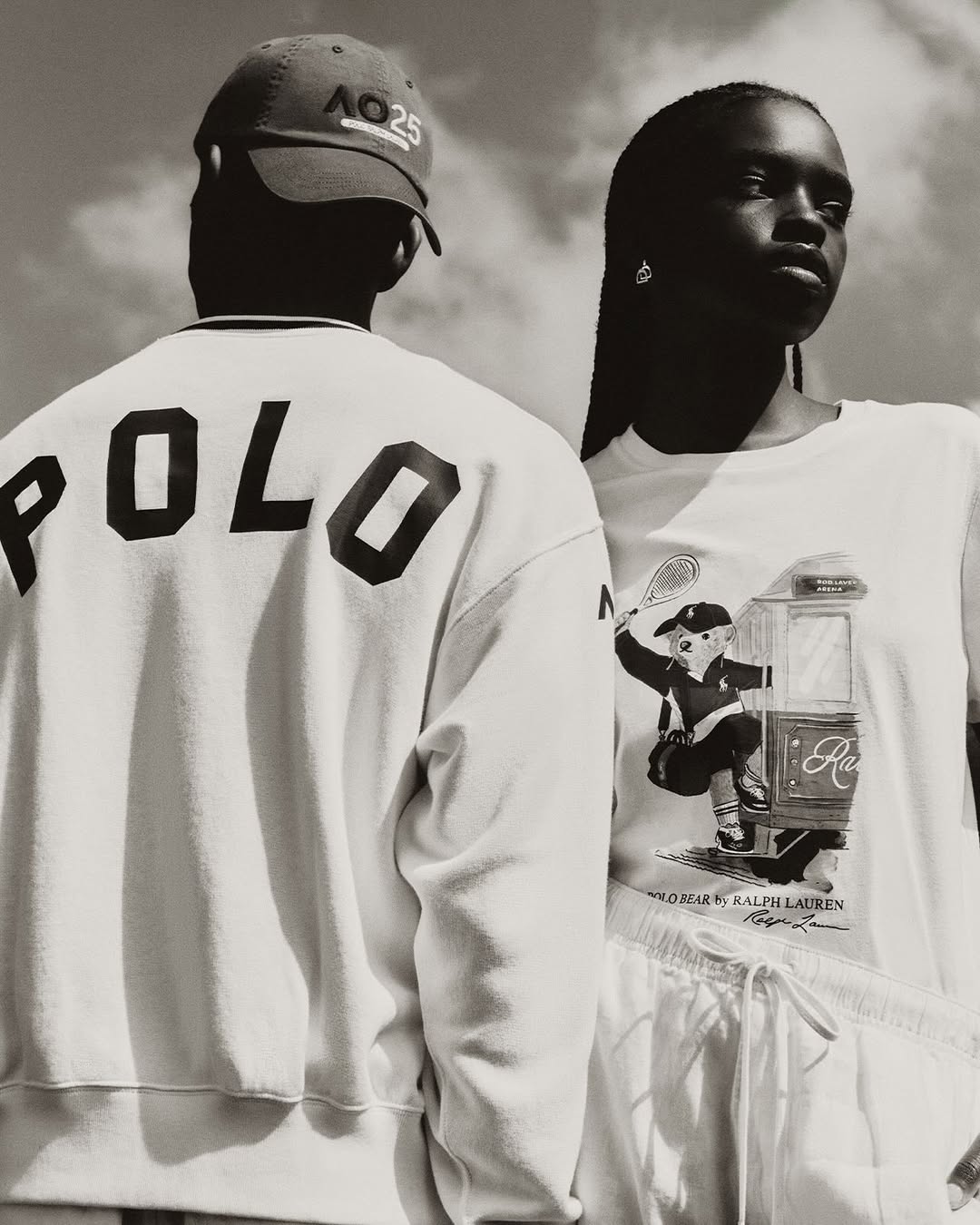 Two fashion models pose outdoors in white Polo Ralph Lauren apparel against a sky background in a monochrome fashion editorial image.