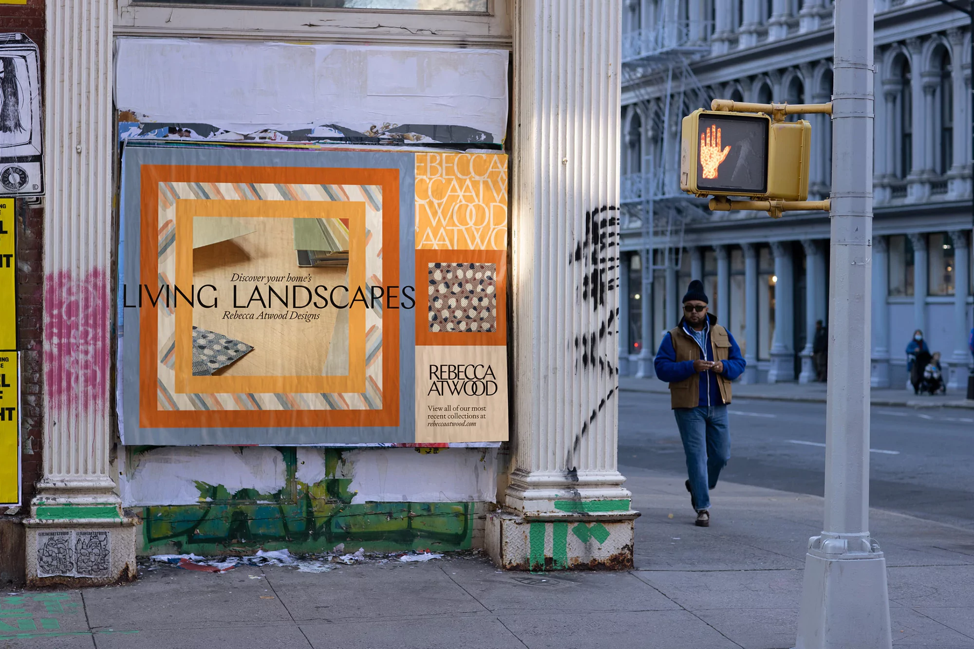 Outdoor urban scene with a Rebecca Atwood design advertisement on a column, and a person walking on the sidewalk of a city street.