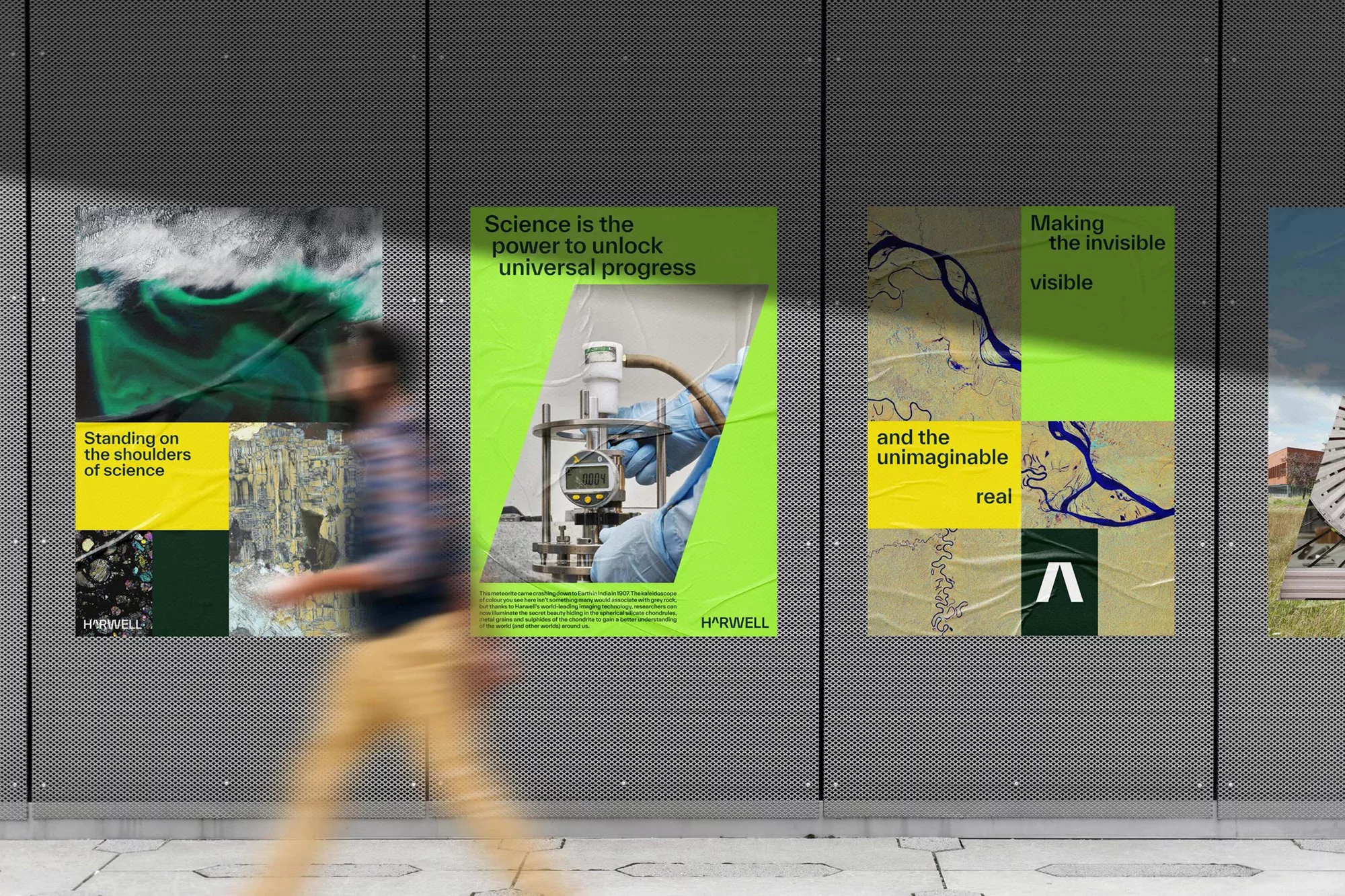 Blurred figure walks past a series of four science posters on a grey tiled wall featuring photomicrography, lab equipment, and typography.