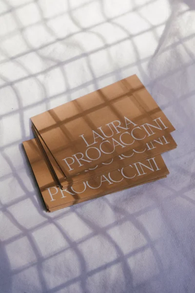 Stack of brown paper business cards featuring white typography under a patterned shadow casting grid lines.