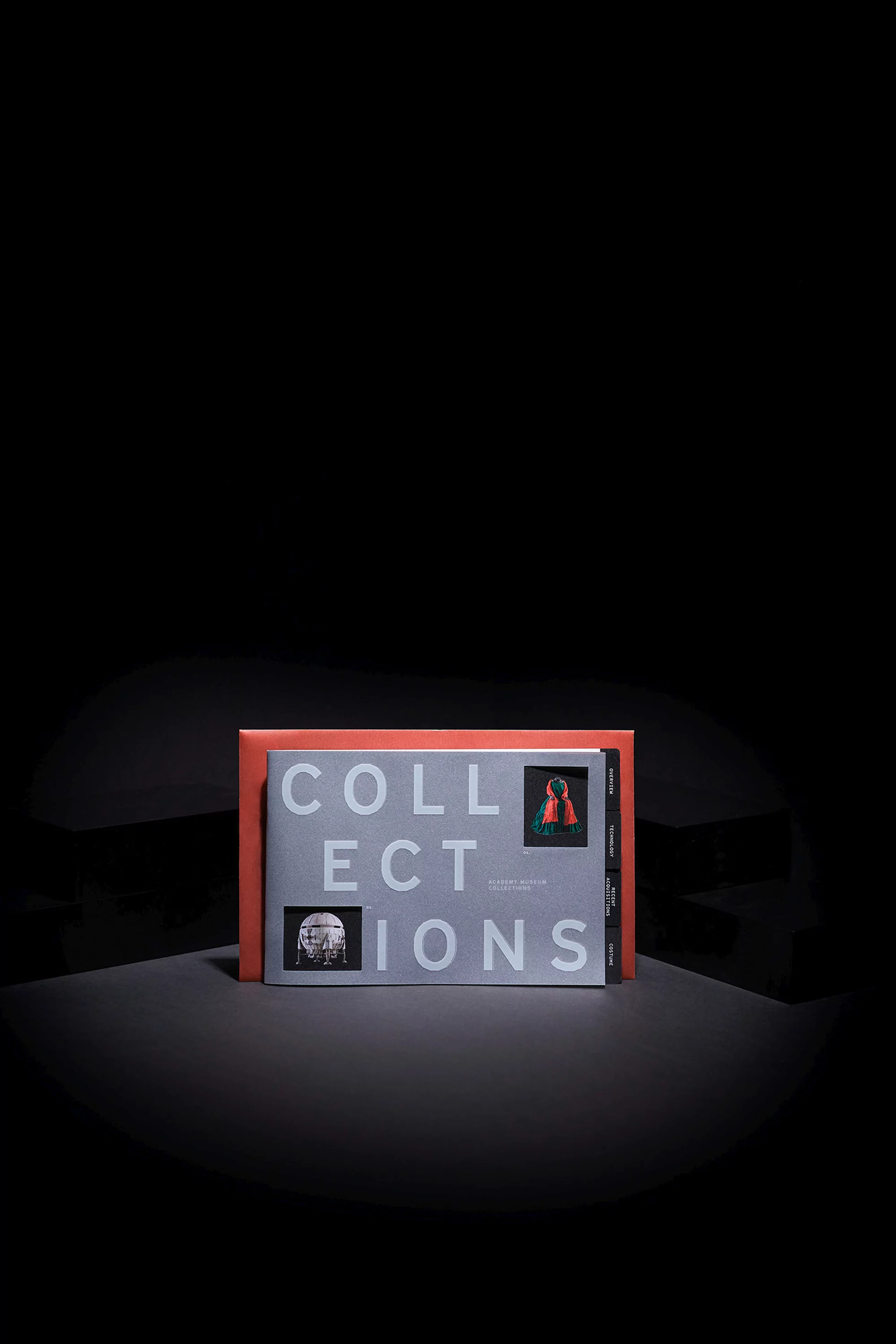 An open book titled 'COLLECTIONS' sits upright, revealing pages with images and text, presented against a solid black backdrop.
