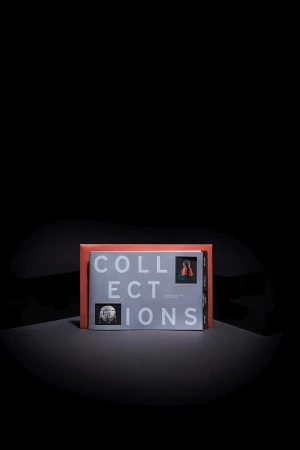 An open book titled 'COLLECTIONS' sits upright, revealing pages with images and text, presented against a solid black backdrop.