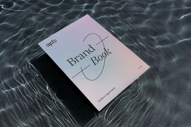 Aplo brand book booklet floating on rippling water reflecting sunlight with typography on the cover