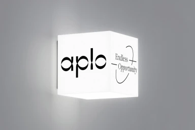 Aplo illuminated brand identity cube sign mounted on a plain grey wall