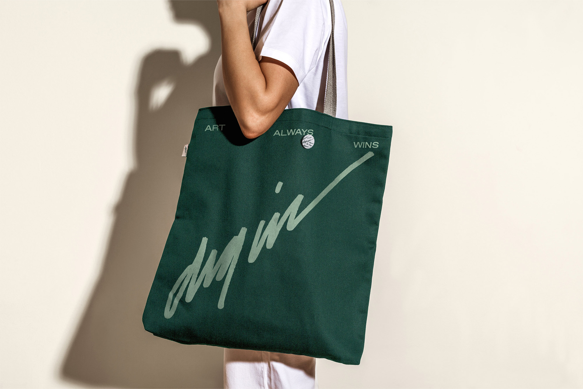 Woman carrying a dark green tote bag with a handle over her shoulder, featuring a handwritten-style print design.