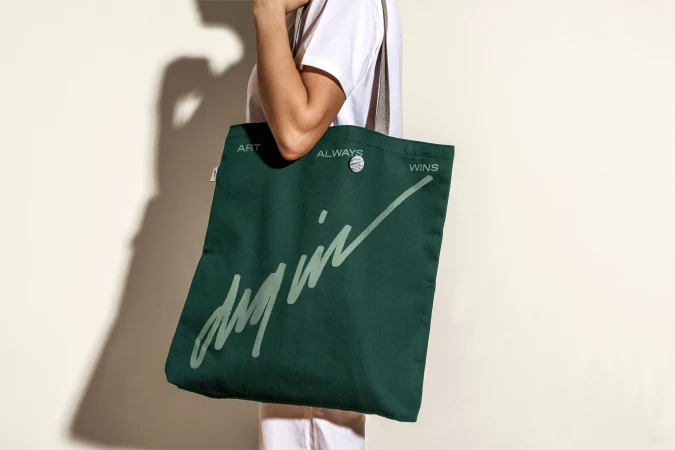 Woman carrying a dark green tote bag with a handle over her shoulder, featuring a handwritten-style print design.