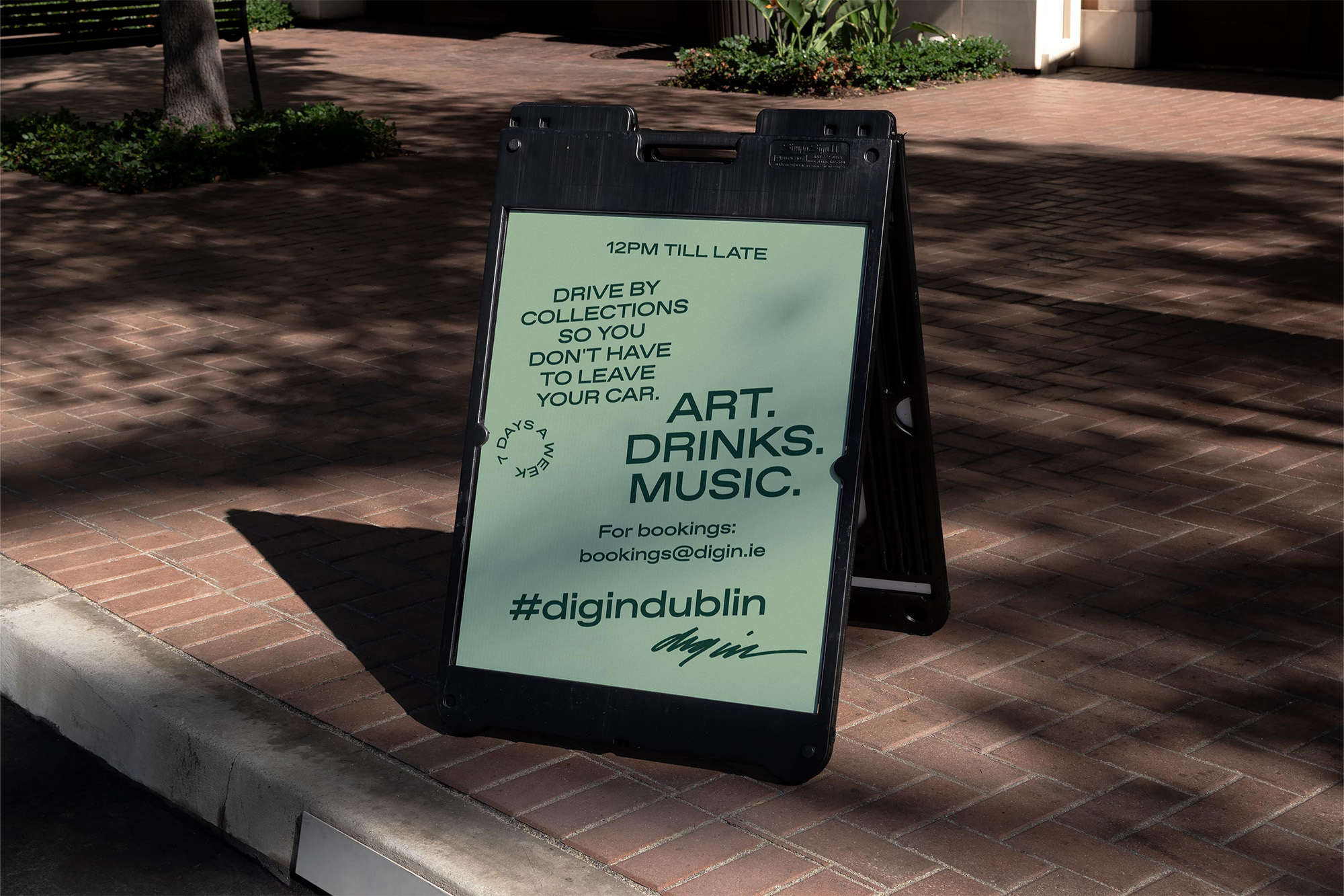 Sidewalk sign advertises a local entertainment venue with information on drive-by collections, art, drinks, and music.