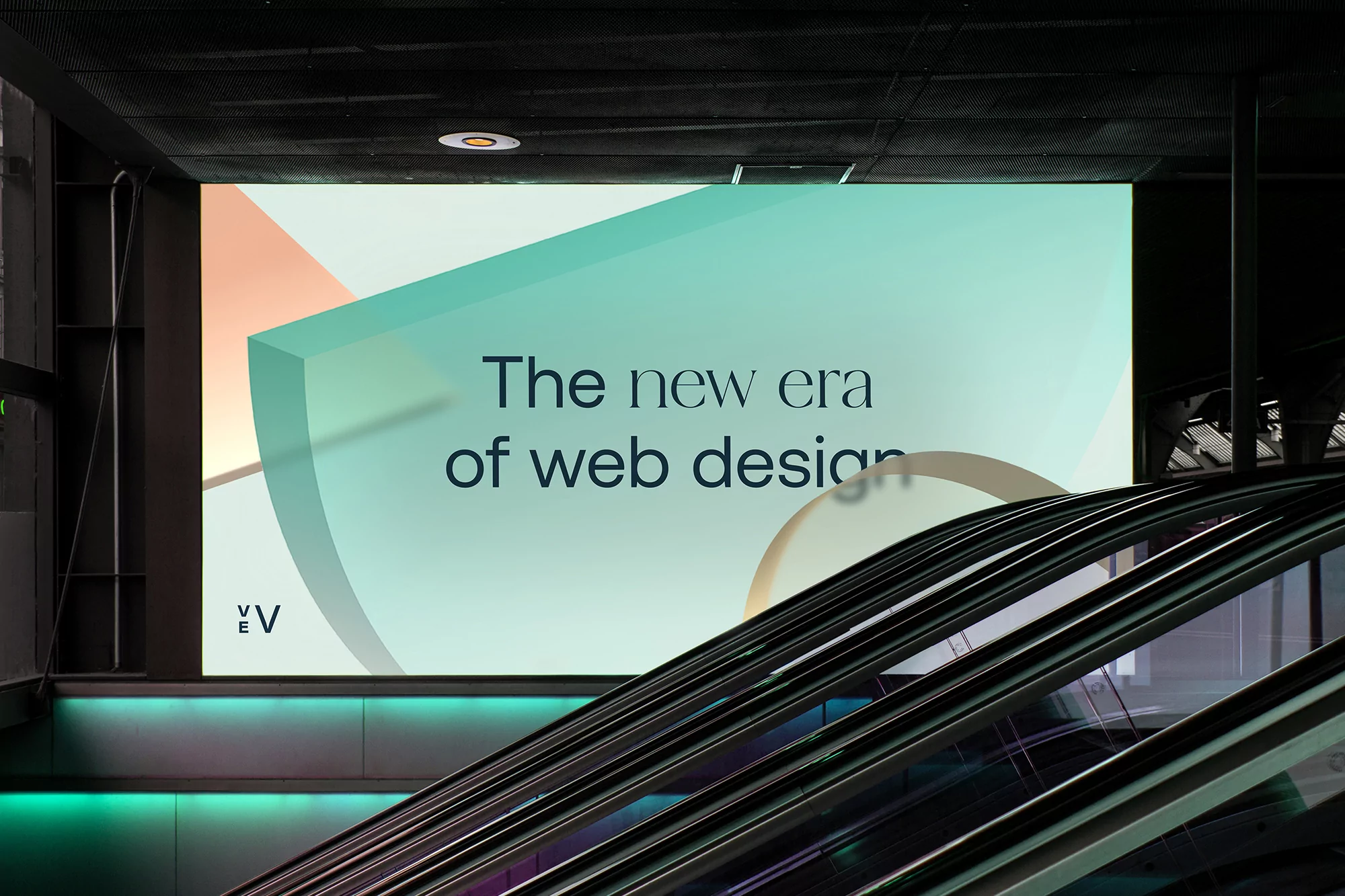 Billboard advertisement featuring graphic design for web design, visible above a modern escalator in an indoor public space.