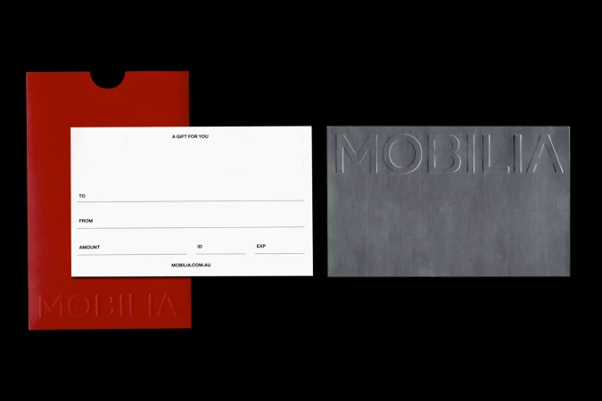 MOBILIA gift cards. One blank white card with fill-in fields, one gray card embossed with the brand name, and a red envelope.