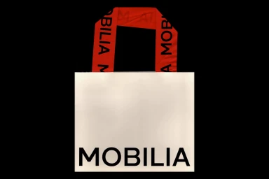 White paper shopping bag with black typography and red fabric handles against a black background