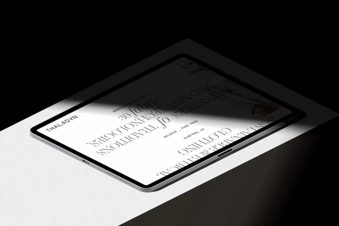 Angled view of a tablet displaying the Thaladyn website, featuring sustainable and ethical clothing against a dark background with light.