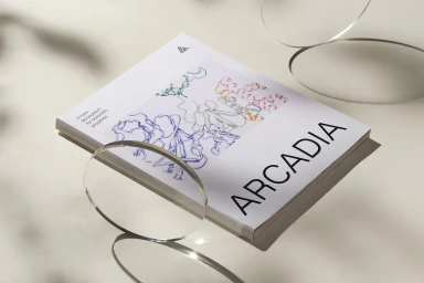 Arcadia Science brand publication book resting on a neutral surface with transparent acrylic disc props casting soft shadows.