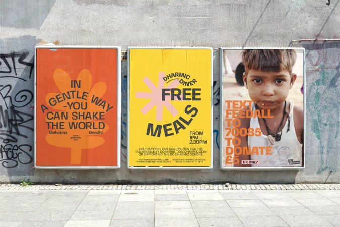 Three colorful charity posters hang on a concrete wall. The posters promote free meals and encourage donations for vulnerable people.
